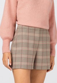 Shorts à carreaux dans des couleurs beige, marron et rose, avec un ourlet renforcé, des poches latérales et une coupe décontractée. Fabriqués en tissu léger.