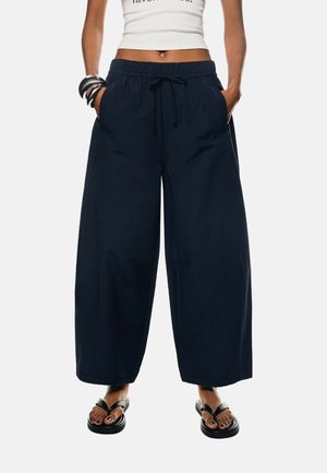 Pantalon large bleu marine avec une taille élastique et un cordon de serrage, doté de poches latérales et fabriqué en coton léger.