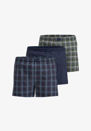 Three pairs of swim trunks: one dark blue, one green plaid, and one navy plaid, all with elastic waistbands and lightweight fabric.