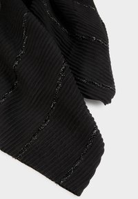 Tessuto nero a coste con fili diagonali scintillanti argento, piegato su uno sfondo grigio chiaro.