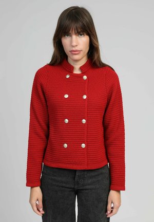 Veste rouge texturée avec un col rond, devant double boutonnage et boutons argentés. Manches longues avec poignets côtelés.