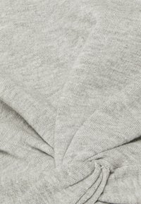 Šedá pletenina má zkroucený design, který ukazuje jemnou texturu s mírně melírovaným vzorem a jednotnou barvou po celém povrchu.