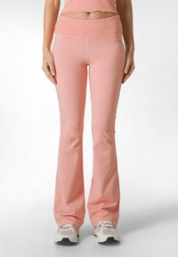 Lichtroze flared broek van zachte stof, met een brede geribbelde tailleband en naadloze zijdetails.