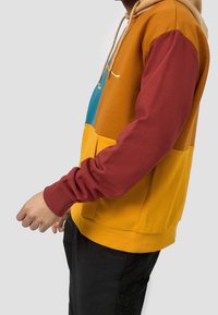 Kleurgeblokkeerde hoodie met oranje, blauw, gele en bordeauxrode panelen. Zachte stof met geribbelde boorden en een kangoeroezak. Capuchon met trekkoord.