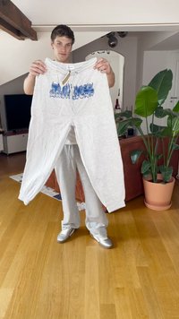 Pantalones deportivos gris claro con cordón blanco, con texto impreso en azul "DARKNESS". Textura suave, corte holgado y puños acanalados.