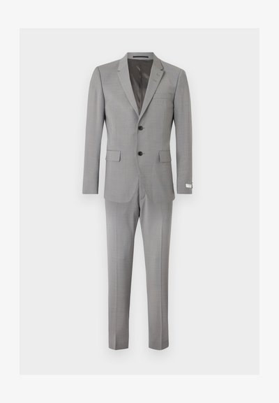 Ανδρικό κοστούμι ανοιχτού γκρι χρώματος με δύο κουμπιά, γιακά με εγκοπή, τσέπες με καπάκι και στενά παντελόνια, απεικονισμένο σε λευκό φόντο.