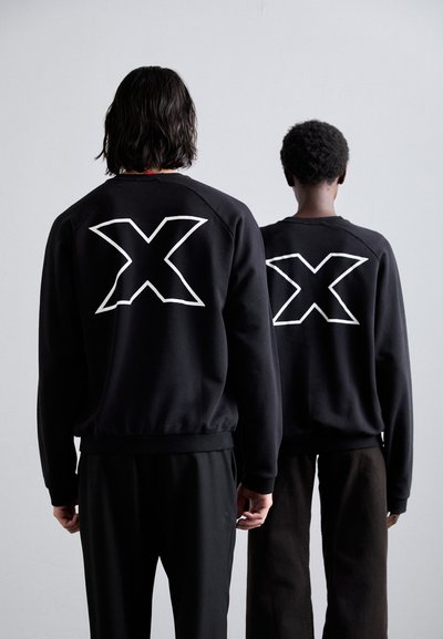 Black sweatshirts featuring large white "X" designs on the back, with ribbed cuffs and hem, paired with black and brown pants.