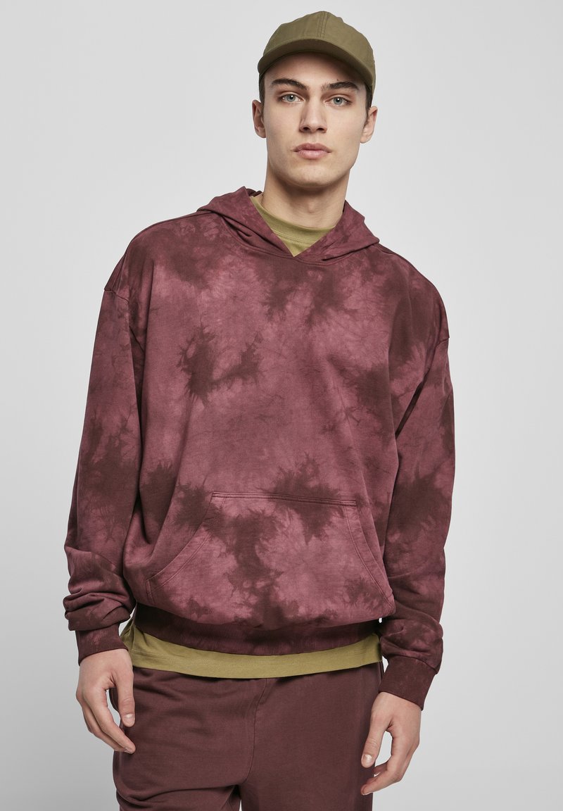 Hanorac bordeaux cu efect tie-dye, dotat cu buzunar tip cangur, manșete și tiv ribbate. Purtați peste un tricou de culoare verde măslin, asortat cu pantalonii.