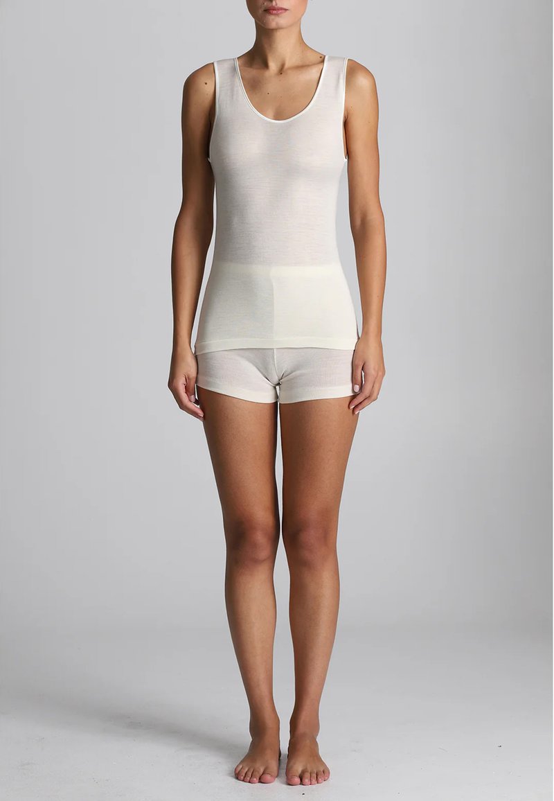 Top in ecrù con scollo a barco e spalline larghe, abbinato a pantaloni corti coordinati. Il tessuto è leggero e aderente.
