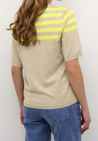 Beige kortærmet sweater med horisontale neon gule og grå striber på ryggen; blød tekstur med en tætsiddende pasform.