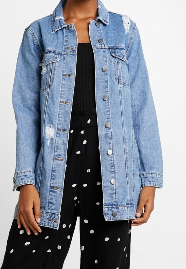 Světle modrá džínová bunda s opranými detaily, zapínáním na knoflíky a límcem. Stylizováno s černým overalem s bílými puntíky.