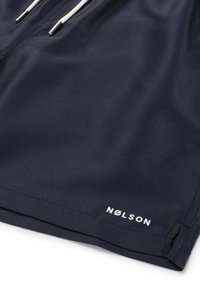 Marine zwemshorts gemaakt van glad, lichtgewicht stof. Voorzien van een elastische tailleband met witte trekkoorden en het "NØLSON" logo in het wit.