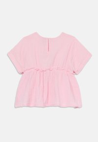 Top blouson rosa con maniche corte, vita arricciata e apertura a chiave sul retro. Realizzato in tessuto leggero con una finitura morbida e strutturata.