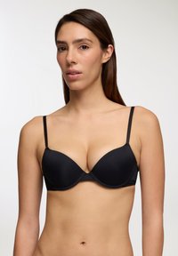 Bra nero con ferretto, dotato di coppe lisce e imbottite. Presenta spalline sottili regolabili e un design minimalista, per un aspetto senza soluzione di continuità.