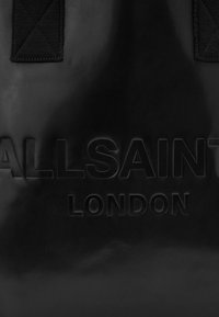 Saco tote de couro preto com a marca "ALLSAINTS LONDON" em relevo, textura mate e alças duplas em tecido com design acolchoado.