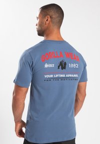 Heren blauwe katoenen t-shirt met een grote rode grafische afbeelding op de achterkant met de tekst "GORILLA WEAR" en een gorilla-illustratie met tekstdetails.