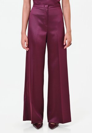 Pantalon large taille haute couleur prune brillante avec une subtile texture à carreaux, porté avec des chaussures pointues assorties, montré de la taille aux pieds.