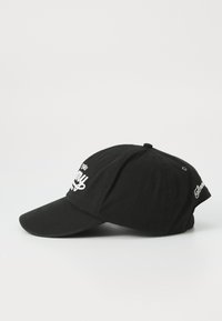 Casquette de baseball en coton noir avec une visière incurvée, ornée d'un texte brodé blanc à l'avant et d'un petit logo sur le côté.