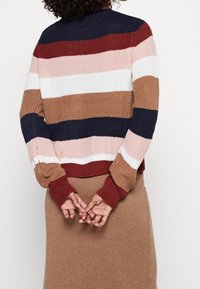 Stickad tröja med djärva horisontella ränder i marinblått, burgundy, vitt, rosa och brunt. Ribbad ärm och nederkant; avslappnad passform.