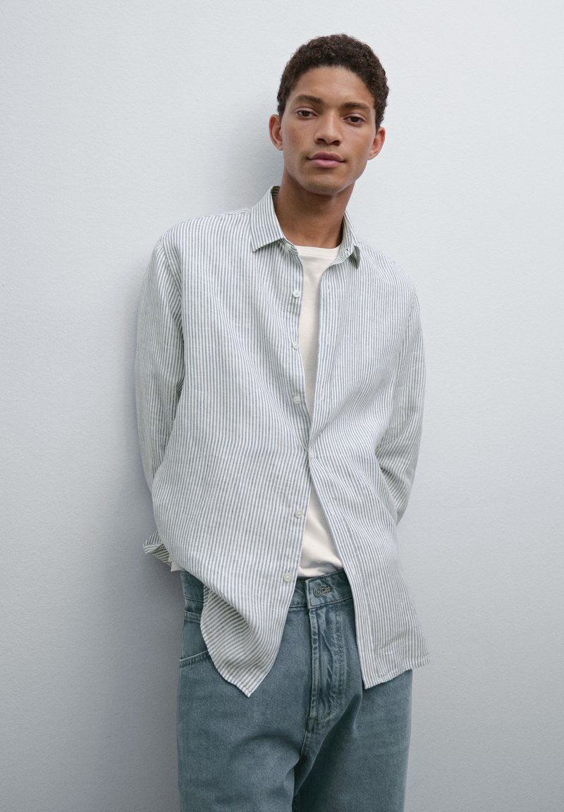 Lichtblauw en wit gestreepte button-up shirt met een kraag, gecombineerd met lichtblauwe denim jeans. Soepele stof, relaxte pasvorm en lange mouwen.