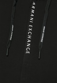Felpa nera con cappuccio dotata di zip, cordini e logo "ARMANI EXCHANGE" in bianco sulla parte anteriore. Tessuto a trama liscia.