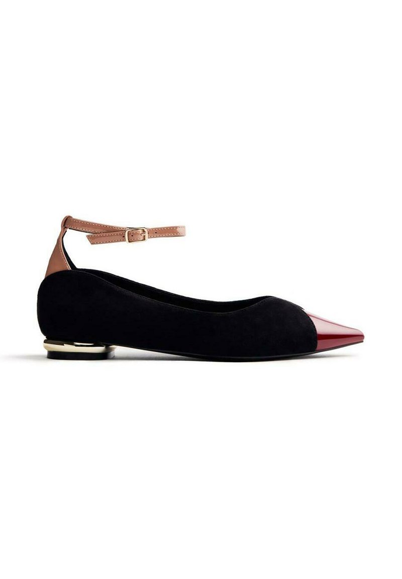 Chaussure plate en suède noir avec un bout pointu en vernis rouge, bride de cheville en marron clair et une accentuation dorée sur le talon. Design et matériaux classiques.