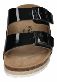 Black patent slide sandal with two adjustable buckles and a natural cork footbed, featuring a textured sole and woven jute accent.