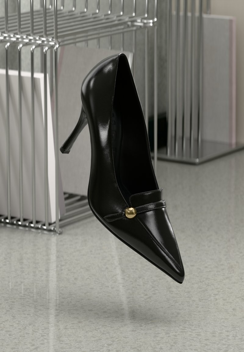 Pantof cu toc înalt din piele neagră, cu vârf ascuțit și detalii cu curea, prezentând un accent auriu. Textură netedă și design elegant.