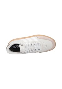 White leather sneaker with beige accents, flat rubber sole, and three white stripes. Features round toe, perforations, and lace-up design.