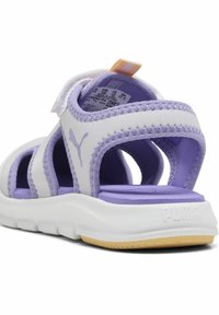 Lila och vita atletiska sandaler med öppen tå-design, justerbar rem, mjukt tygöverkänd, texturerad lila innersula och vit gummiyttersula.