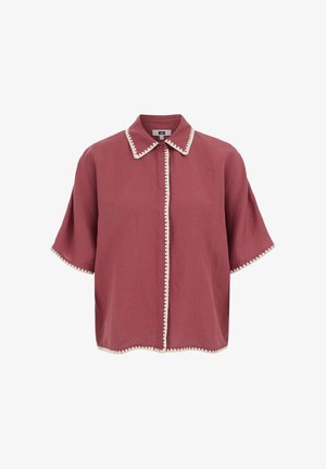 Camicia rosa polvere a maniche corte con bordatura a zigzag bianca su collo, patta frontale, maniche e orlo, con un solo bottone superiore visibile.