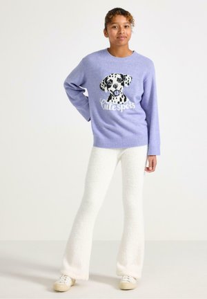 Jasnofioletowy dzianinowy sweter z grafiką dalmacji i napisem "Słodkie cętki"; w zestawie z białymi rozszerzanymi spodniami i białymi trampkami.