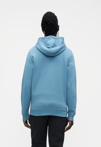 Sudadera azul con capucha y ajuste relajado. Confeccionada en algodón, presenta puños y dobladillo acanalados, textura suave y diseño con bolsillo tipo canguro.