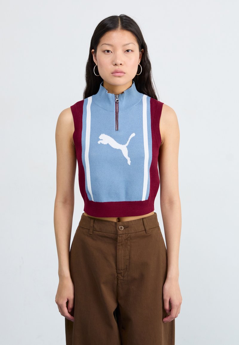 Gebreide mouwloze top met een ritskraag, met lichtblauwe en bordeauxrode secties en een wit Puma-logo, weergegeven tegen een neutrale achtergrond.