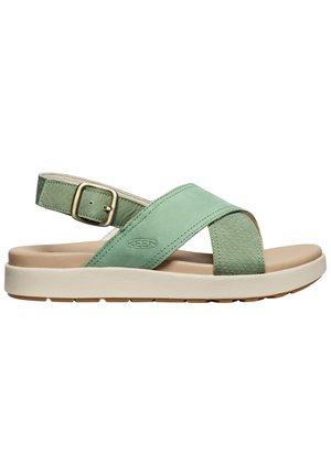 Sandalo verde in pelle con cinturini incrociati, fibbia regolabile, suola imbottita beige e dettagli strutturati sulla cinghia posteriore e sul pannello laterale.