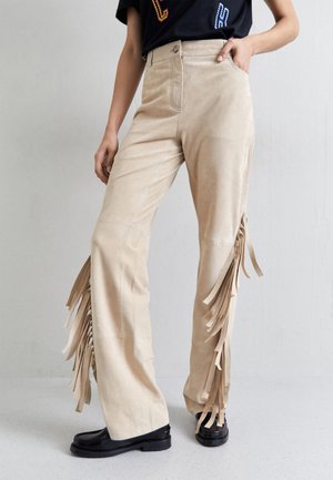 Beige σουέτ παντελόνι με φαρδιά γραμμή και φούντες στις πλαϊνές ραφές. Διαθέτει μπροστινές τσέπες και ζωνάκι με κουμπί.