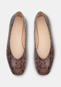Zapatos planos tipo slip-on con estampado de piel de serpiente marrón, punta redonda y plantillas beige, vistos desde arriba sobre un fondo blanco.