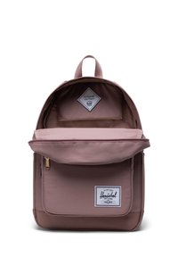 Backpack with a soft pink fabric exterior, featuring a zippered front pocket, a rectangular shape, and a white branded patch on the front.