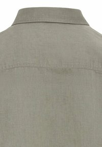 Lichtgrijs linnen overhemd met een kraag. Heeft een subtiele textuur en stiknaden langs de halslijn en schouders. Eenvoudige, strakke afwerking.