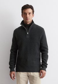 Dark gray knit pullover with a half-zip collar, ribbed cuffs and hem, and a textured pattern. Worn over a black turtleneck.