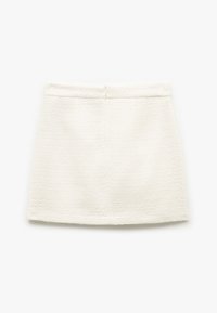 Hvid vævet nederdel med en struktureret overflade, lige snit, flad talje og lynlås i ryggen. Ingen synlige lommer eller udsmykninger.