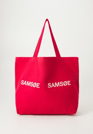 Red fabric tote bag with two white "SAMSØE" logos at an angle. Features two sturdy short handles. Smooth texture, simplistic design.