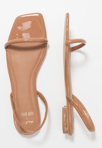 Kashmiri kein hiekkalyhteetä, kiiltävä pinta, neliön muotoinen varvas, ohuet hihnat ja tasainen korko. Teksturoitu pohja on näkyvissä.