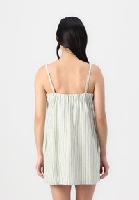 Camisón ligero a rayas con tirantes finos, de espalda fruncida para mayor comodidad. Colores: verde pálido y blanco.