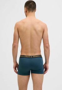 Férfi boxer alsónadrág téglalap formában, zöld színű anyaggal és fekete derékkal, arany "JACK & JONES" márkajelzéssel. Simaság jellemzi, testhezálló formájú.