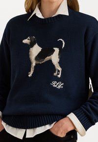 Marine gebreid trui met een grafisch ontwerp van een hond, geribbelde halslijn en manchetten, en een witte geborduurde logo aan de onderkant.