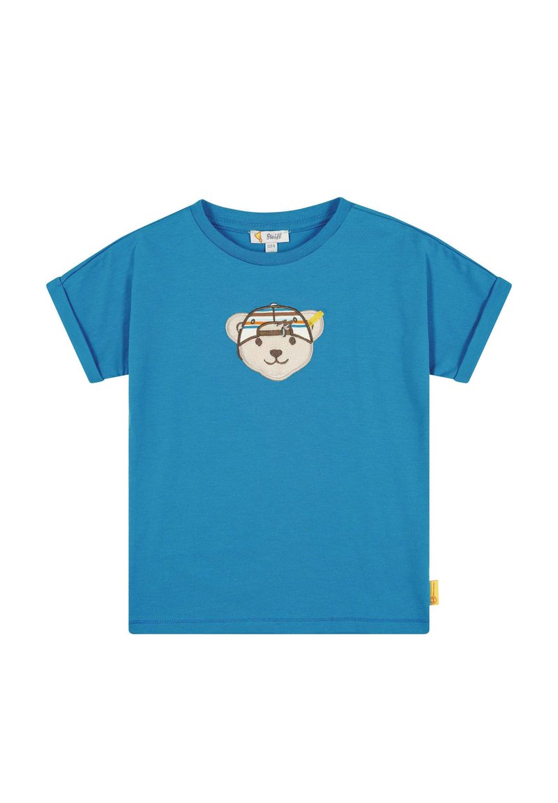 Camiseta azul de manga corta hecha de algodón, con una cara de oso bordada en la parte frontal con un diseño colorido y una etiqueta amarilla en el costado.