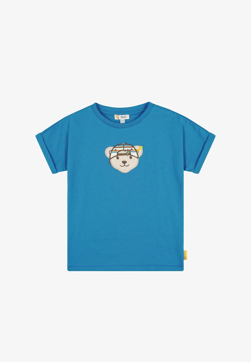 Modré tričko s krátkým rukávem vyrobené z bavlněného materiálu, na přední straně s vyšívanou tváří medvěda v barevném designu a žlutou nášivkou na boku.