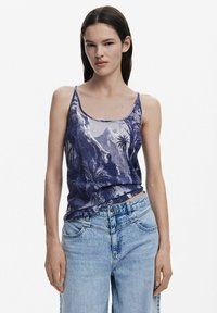 Modrá top s tenkými ramienkami, zdobený vzorom hory a palmových stromov, spárovaný so svetlomodrými riflami s širokým strihom. Hladká textúra.