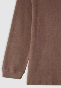 Brązowy sweter z miękkiej, teksturowanej tkaniny, z długimi rękawami i prążkowanymi mankietami. Design jest prosty, bez widocznych wzorów czy dodatków.